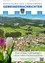 Luftaufnahme eines malerischen Dorfes umgeben von grünen Feldern und Bergen. Im Vordergrund stehen weiße und lila Tulpen. Der Text lautet 'Einen schönen Frühlingsbeginn'.