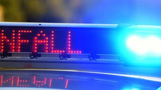 Nahaufnahme eines blinkenden blauen Lichts und einer roten LED-Anzeige mit dem Wort FALL auf einem Polizeiauto.