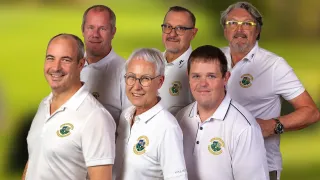 Eine Gruppe von sechs Personen in weißen Poloshirts mit Logos steht eng beieinander und lächelt für ein Foto.