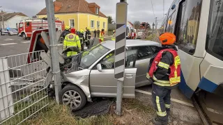 Ein beschädigtes Auto steht am Straßenrand. Rettungskräfte sind vor Ort. Ein Tram ist in der Nähe angehalten.