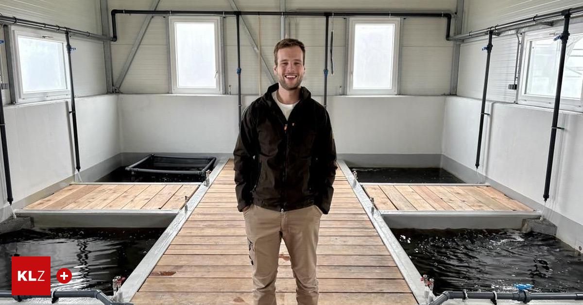 Ein Mann steht auf einem hölzernen Steg in der Nähe von Fischbecken und lächelt für ein Foto. Der Steg hat Geländer, und es gibt drei mit Wasser gefüllte Becken. Der Bereich hat weiße Wände und Fenster.