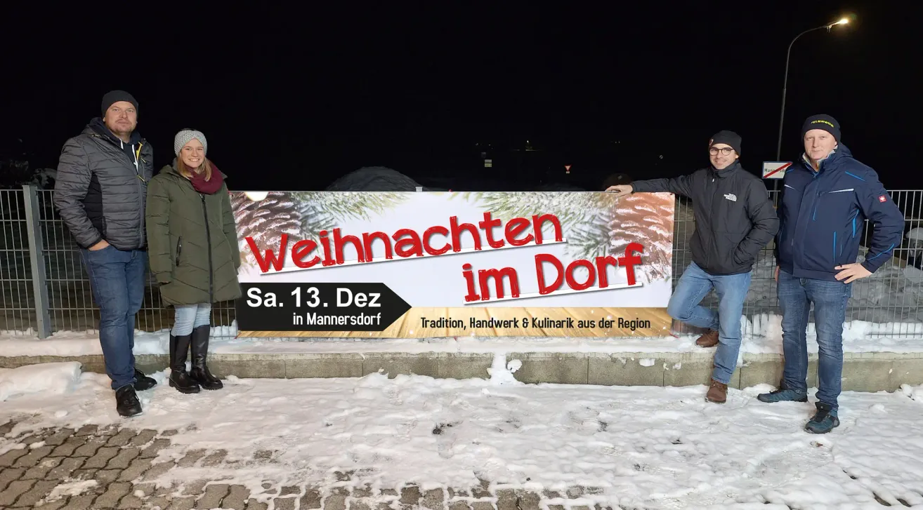 Ein Banner für das Weihnachtsdorf-Event, geplant für Samstag, 13. Dezember, wird an einem verschneiten Tag im Freien ausgestellt. Eine Person steht daneben.