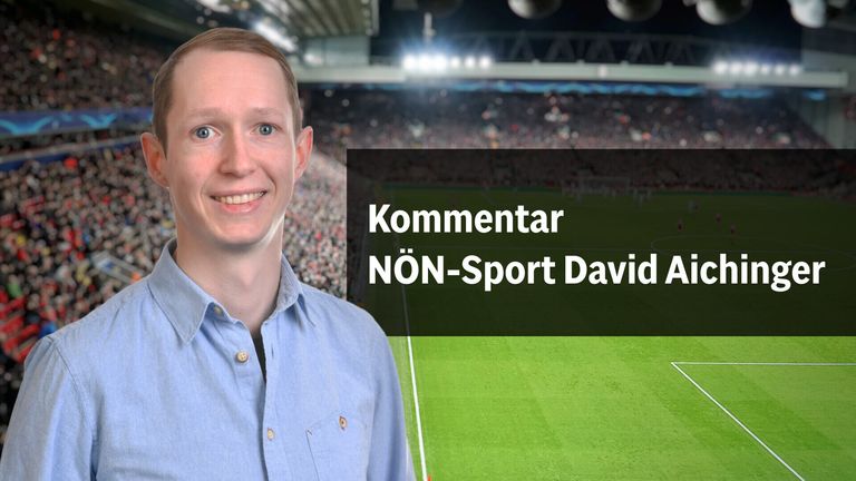 Ein lächelnder Mann mit einem blauen Hemd steht vor einem Fußballfeld mit einer Menschenmenge im Hintergrund. Die Worte 'Kommentar NÖN-Sport David' erscheinen in weiß auf schwarzem Hintergrund.