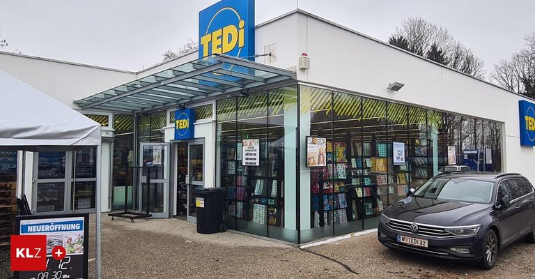 Ein TEDI-Laden mit einer Glasüberdachung und Regalen voller Bücher. Ein schwarzer Wagen ist davor geparkt.