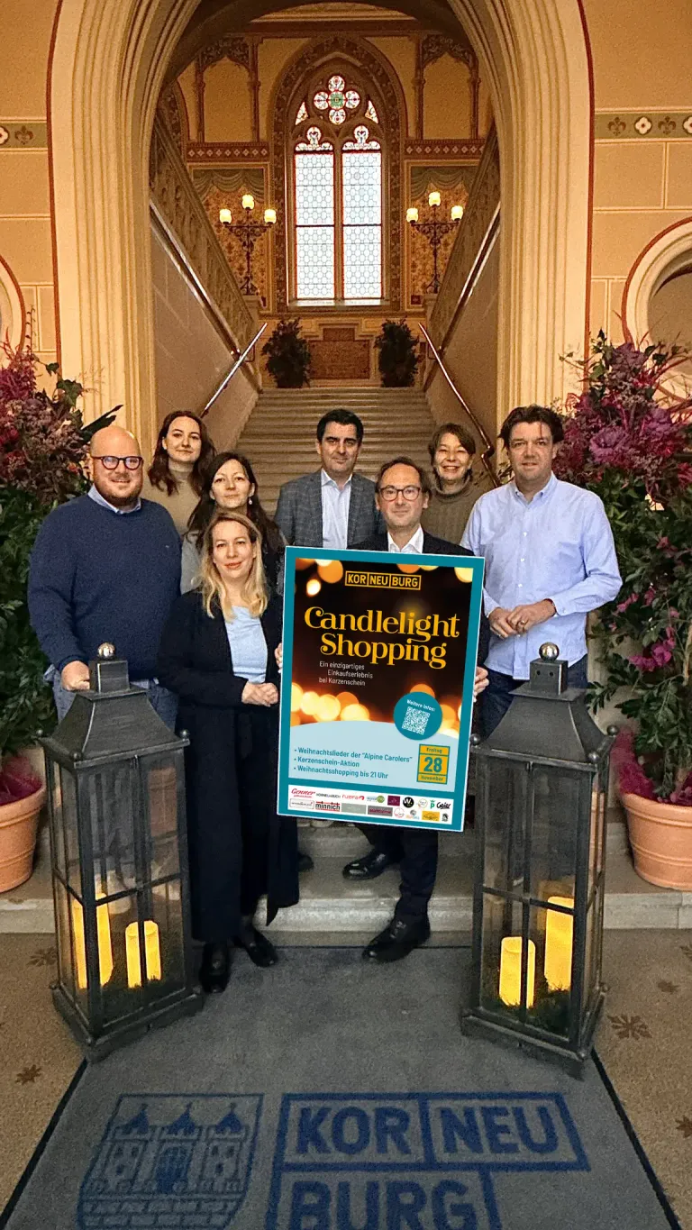Gruppe von Menschen steht auf Stufen und hält ein Schild für Candlelight Shopping. Sie lächeln und posieren für ein Foto.