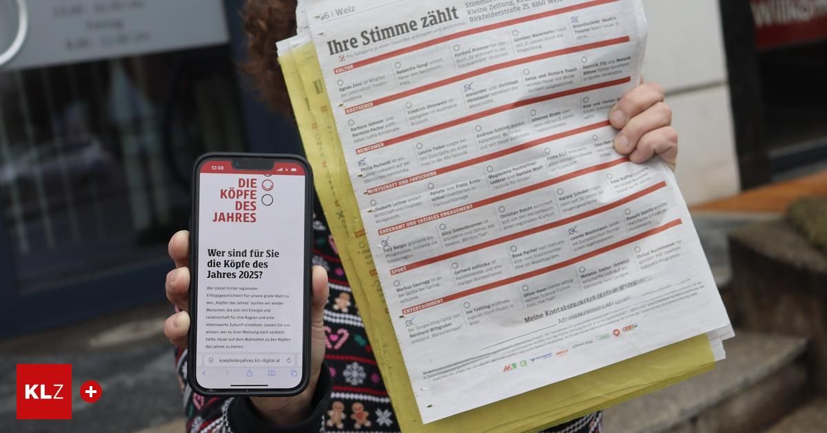 Eine Person hält ein Telefon mit der Anzeige 'Sind wir für die Köpfe des Jahres 2025?' und eine Zeitung mit der Überschrift 'Ihre Stimme zahllt'. Das Telefon ist schwarz und die Zeitung hat einen weißen und roten Hintergrund mit einem gelben Rand.