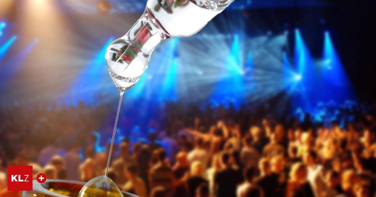 Eine klare Flüssigkeit wird bei einem lebhaften Konzert in ein Glas gegossen, während ein Publikum die Aufführung genießt.