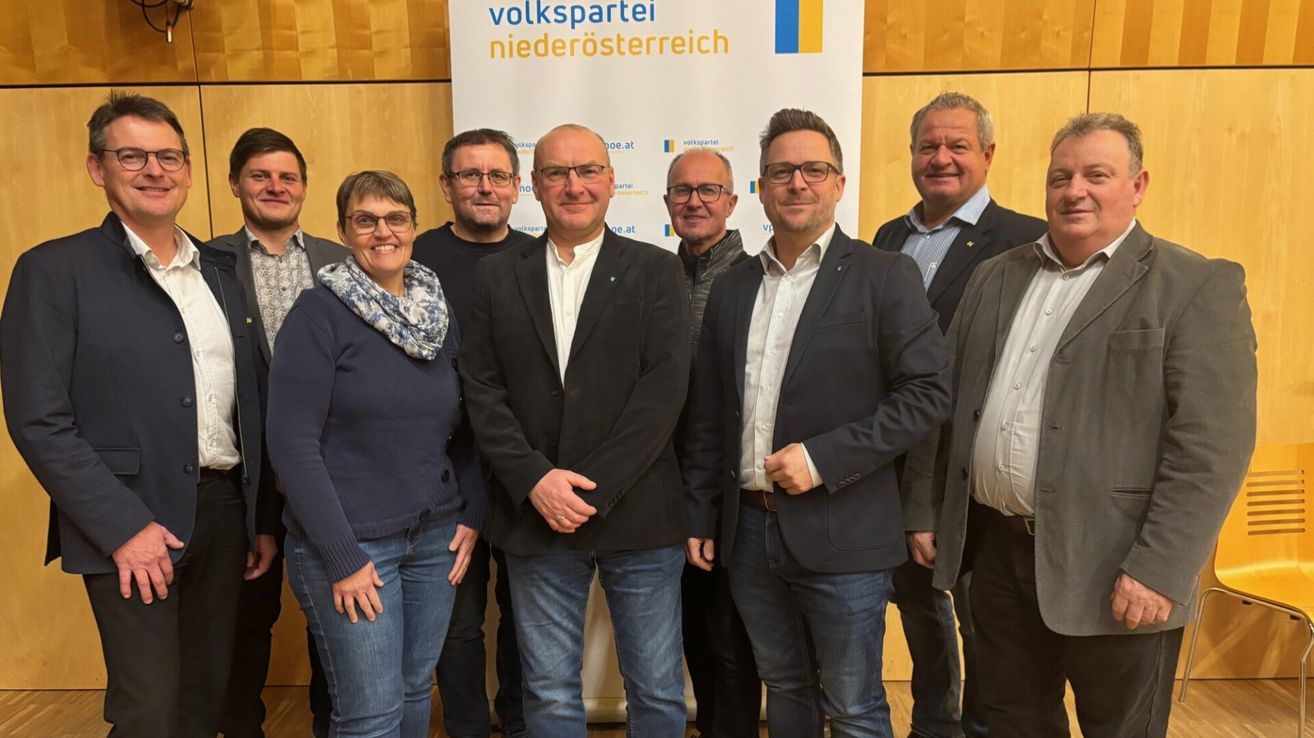 Eine Gruppe von Männern und Frauen, alle formell gekleidet, posiert für ein Foto vor einem weißen Banner mit der Aufschrift 'Volkspartei Niederosterreich.'