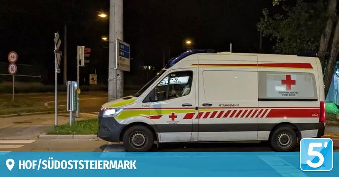 Ein Krankenwagen steht nachts auf der Straße, mit einem roten Kreuzsymbol an der Seite und einem roten Licht oben.
