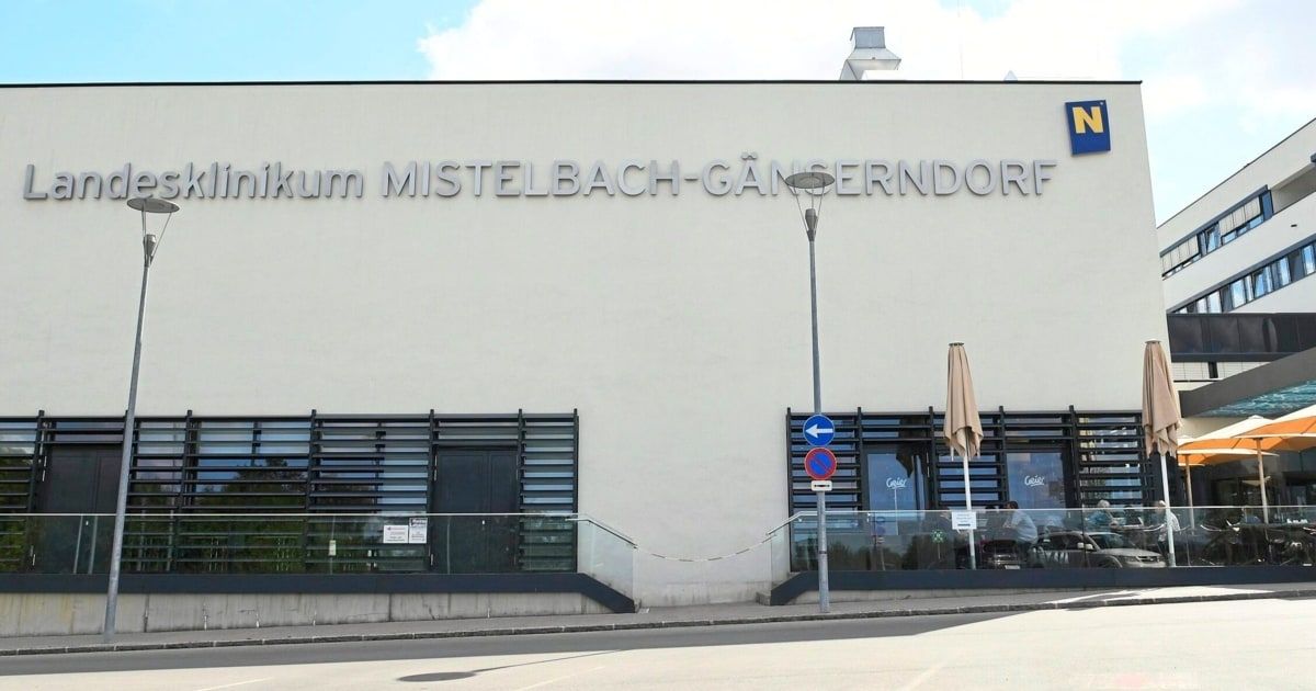 The exterior of a medical facility named 'Klinikum Mistelbach-Ganserndorf' with a glass entrance and a lamp post in front.