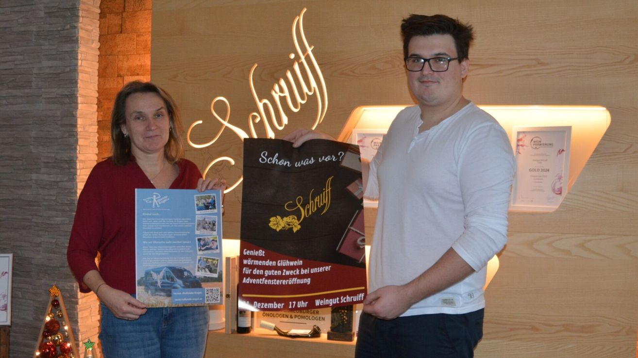 Zwei Personen stehen vor einem Schild. Der Mann hält ein Poster für eine Veranstaltung am 17. Dezember, während die Frau einen blauen Flyer mit Bildern eines Vans und Menschen in der Hand hat. Hinter ihnen ist eine Holzwand mit leuchtenden Buchstaben, die Schriuff lesen.