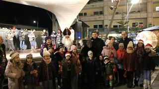 A group of children and adults pose for a photo with a man dressed as Santa Claus and a man dressed as a monster.