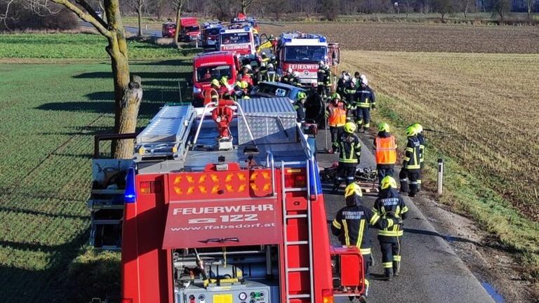 Rettungskräfte reagieren auf einen Unfall mit mehreren Fahrzeugen auf einer Landstraße, mehrere Feuerwehrwagen und Personal sind vor Ort.