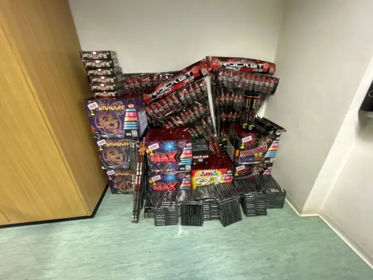 Eine Auswahl an Feuerwerkskörpern in einem Raum, darunter Drachen-, Raketen- und Max-Serien, in Schachteln auf dem Boden gestapelt.