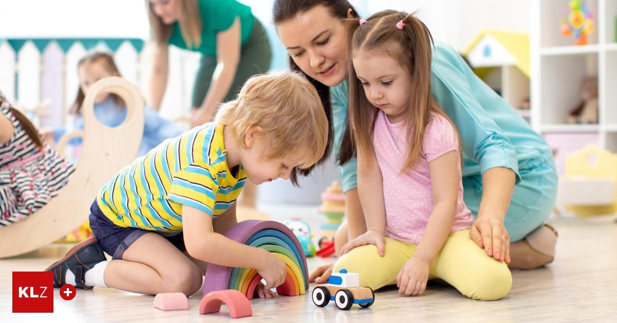 Ein junger Junge und ein junges Mädchen spielen in einem Spielzimmer mit einem Regenbogen und einem Spielzeugauto auf dem Boden. Eine erwachsene Frau beobachtet sie.