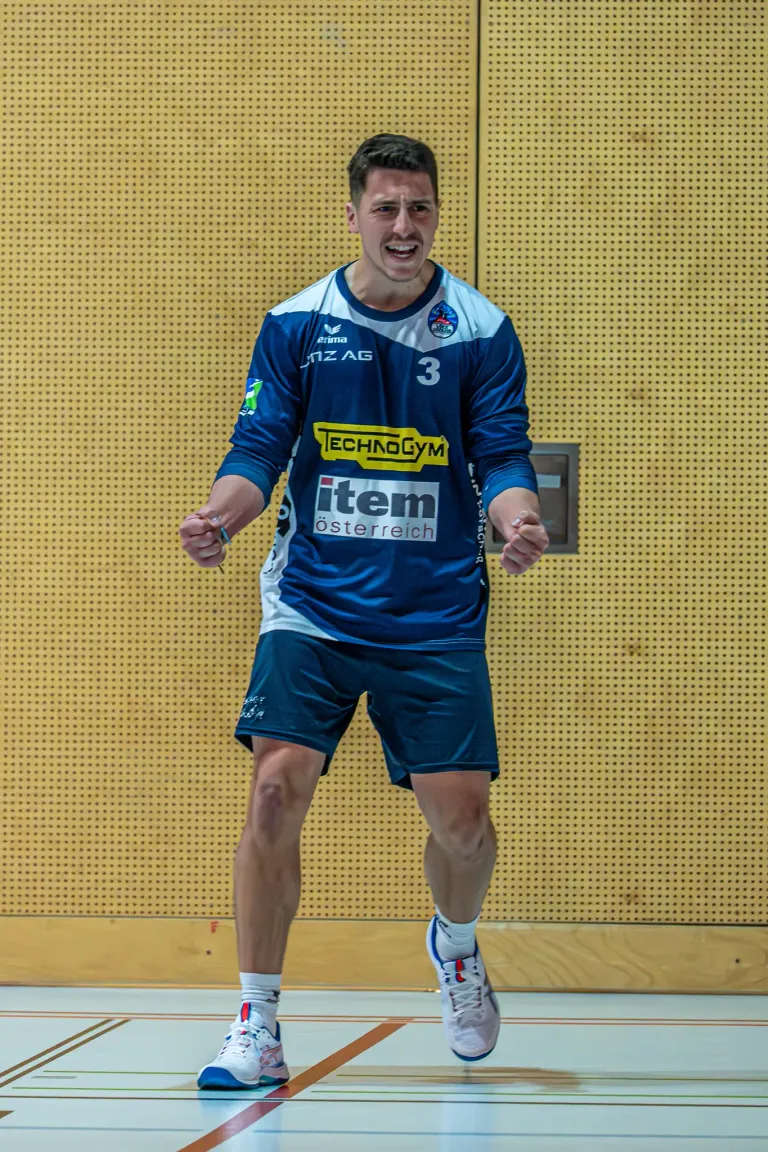 Ein lächelnder Mann in einem blau-weißen Sporttrikot mit der Nummer 3 und item osterreich darauf geht nach vorne.