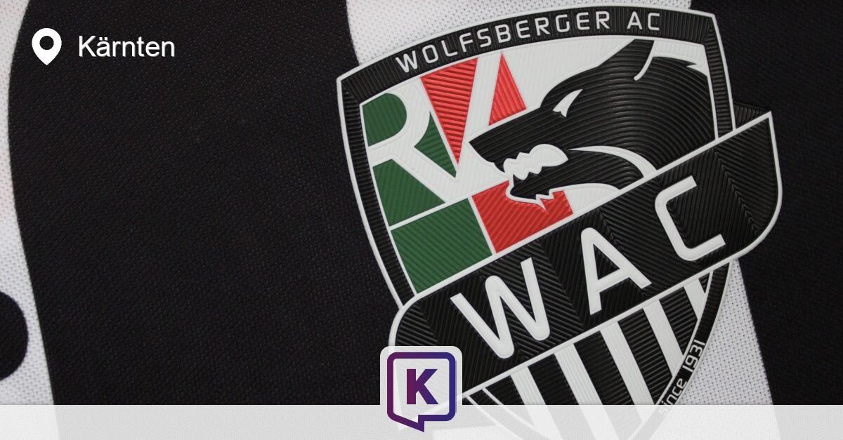 Ein Logo für den Fußballverein Wolfsberger AC, mit einem Wolfskopf, grünen und roten Streifen und dem Text 'WA'. Darunter befindet sich ein violettes 'K' Logo.