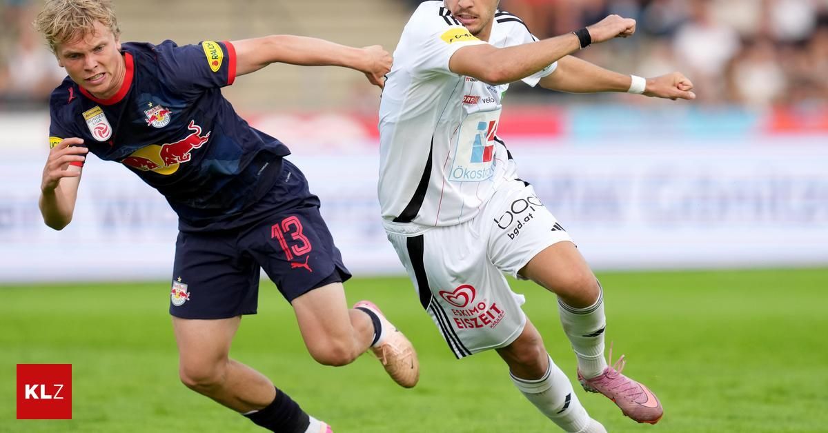 Zwei Fußballspieler, einer in einem blauen Trikot und der andere in einem weißen Trikot, kämpfen auf dem Feld.