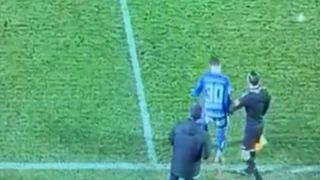 Drei Spieler auf einem Rasenfeld, einer mit Trikotnummer 30, ein anderer mit einer Flagge, diskutieren in der Nähe der Ecklinie.