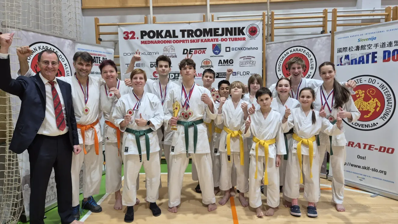 Eine Gruppe junger Karate-Teilnehmer in weißen Uniformen und Medaillen, die bei der 32. Pokal Tromejunik Internationalen Karate-Wettbewerb für ein Foto posiert.