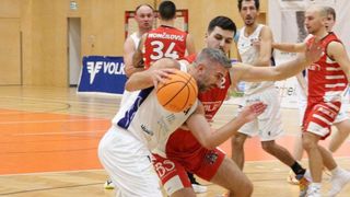 Fünf Basketballspieler spielen auf einer Halle. Ein Spieler dribbelt, während ein anderer versucht, ihn zu blocken. Der Spieler im roten Trikot trägt die Nummer 34.