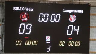 Ein Anzeigetafel zeigt ein Sportspiel zwischen Bulls Weiz und Langenwald mit den Ergebnissen 09 und 04. Das Spiel befindet sich in der dritten Periode, und die Uhr zeigt 00:00 an.