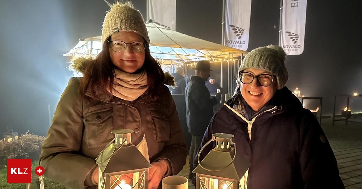 Zwei Frauen halten Laternen und lächeln für die Kamera in einem festlichen Ambiente mit Zelten und Fahnen.
