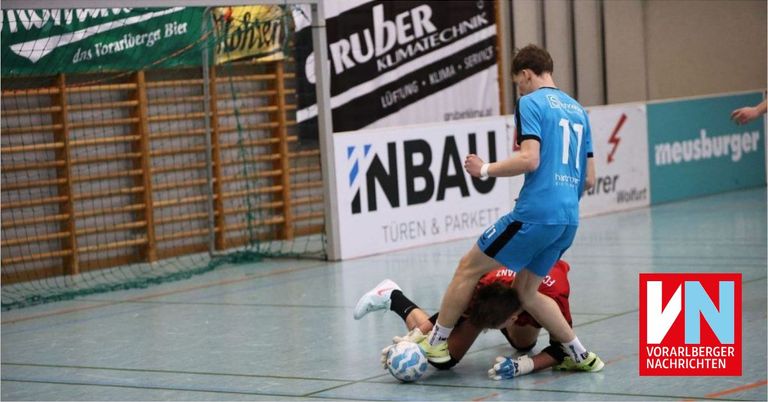Zwei Männer spielen Futsal in einer Halle. Der Spieler in Blau trägt das Trikot mit der Nummer 11 und ist dabei, den Ball zu schießen. Der Spieler in Rot liegt auf dem Boden.