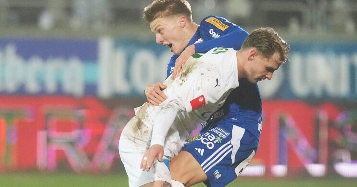 Zwei Fußballspieler in blauen und weißen Trikots sind auf dem Feld in einem engen Match und kämpfen intensiv.