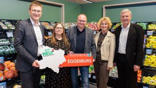 Five people stand in a grocery store, smiling for the camera. They hold a sign reading 'Jetzt Neu! EuroSpar Eggenburg.' Behind them are shelves with various fruits and vegetables.