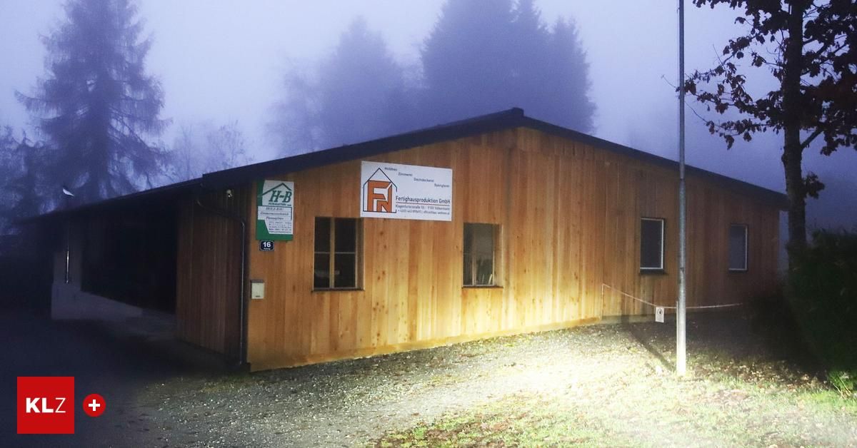A wooden building with a sign reading 'Fertigungsproduktion GmbH' stands in a foggy landscape. The building has three windows and a number 16 sign on the wall.