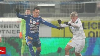 Two soccer players in action, one in blue and one in white, both wearing gloves and actively engaging in a match.