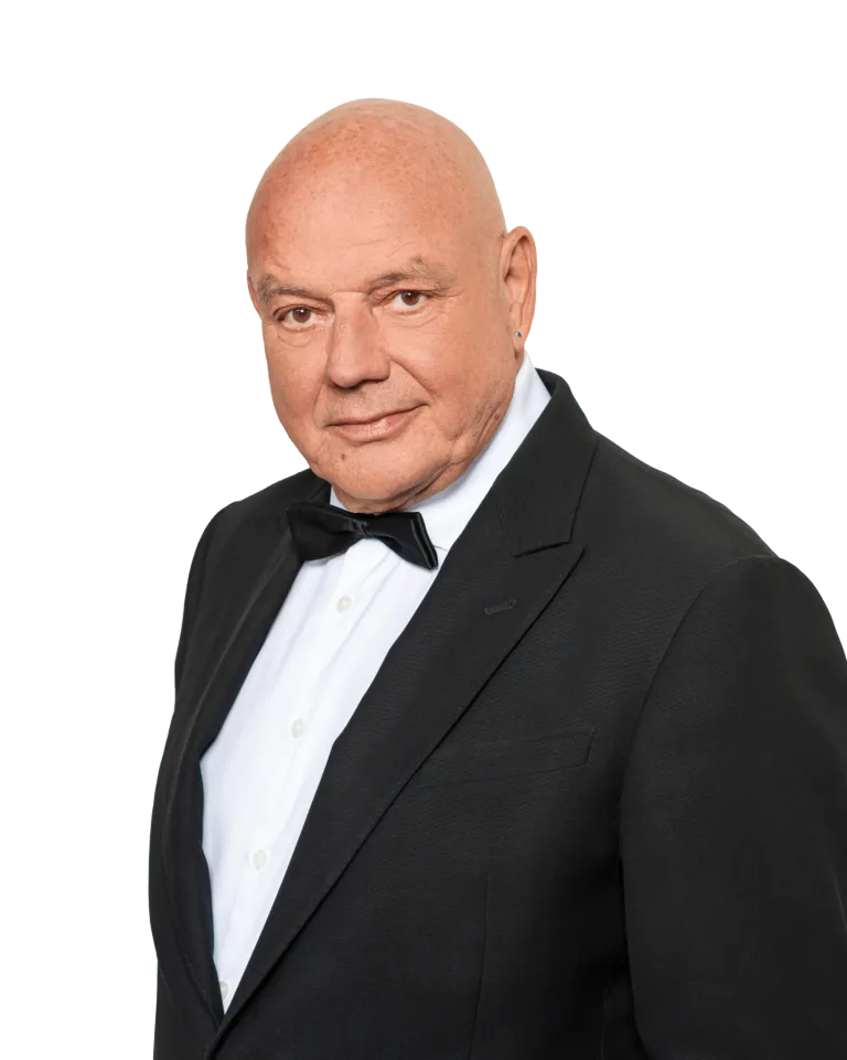 Ein Mann mit kahlem Kopf und Lächeln trägt einen schwarzen Anzug mit weißem Hemd und schwarzer Fliege.