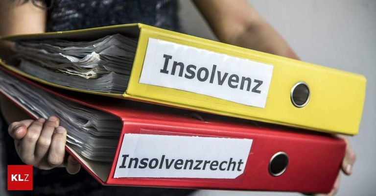 Zwei Ordner gestapelt, einer mit der Aufschrift 'Insolvenz' und der andere mit 'Insolvenzrecht', beide mit vielen Seiten innen, gehalten vom Arm einer Person.