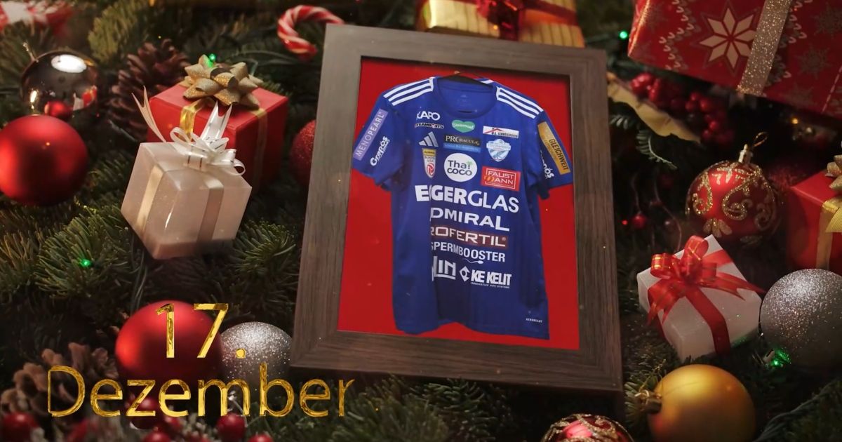 Ein gerahmtes Trikot mit Sponsorenlogos, das auf einem Weihnachtsbaum ausgestellt ist. Das Trikot ist blau mit weißen Texten. Unter dem Rahmen steht das Datum '17. Dezember'. Geschenke umgeben den Rahmen.