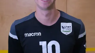Ein Mann mit einem lächelnden Gesicht steht in einem Fitnessstudio und trägt ein schwarzes und graues Sporttrikot mit der Nummer 10 und dem Wort Augusta.