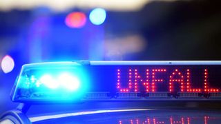 Ein Polizeiauto mit eingeschalteten Lichtern zeigt das Wort 'POLIZEI' in roten Lichtern oben an. Die blauen Lichter leuchten seitlich.