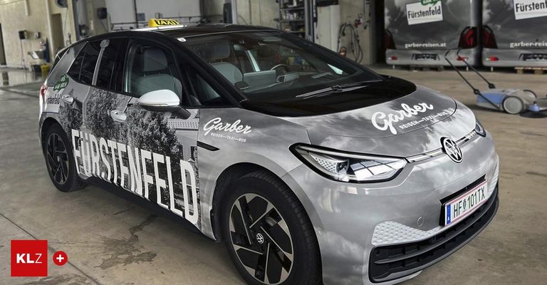 Ein silberner Wagen mit dem Wort 'Garber' an der Seite steht in einer Garage. Oben befindet sich ein Taxischild.