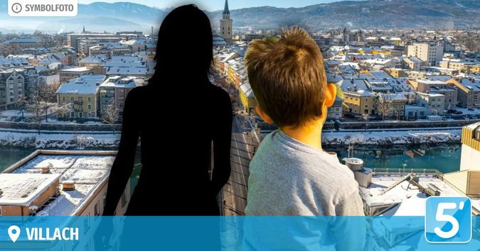 A silhouetted woman and a boy stand on a rooftop, gazing at a snowy town with a river and mountains in the distance. The image is labeled 'Villach.'