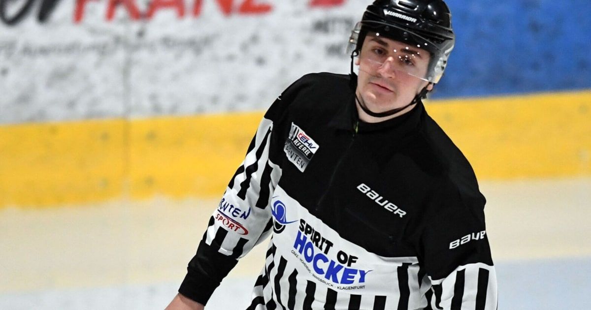 Ein Eishockeyspieler ist auf dem Eisfeld und trägt ein schwarz-weiß gestreiftes Schiedsrichtertrikot, einen schwarzen Helm und klare Brille. Das Trikot hat die Aufschrift Spirit of Hockey auf der Vorderseite.