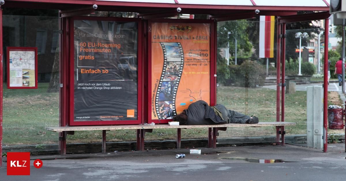 Ein Mann schläft auf einer Bank unter einer Bushaltestelle. Der Schutzraum hat Werbung für Orange und Casino.