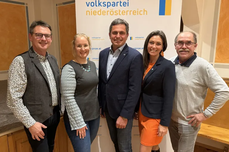 Fünf Personen stehen lächelnd vor einem Hintergrund mit der Aufschrift 'Volkspartei Niederosterreich'. Sie sind formell gekleidet.