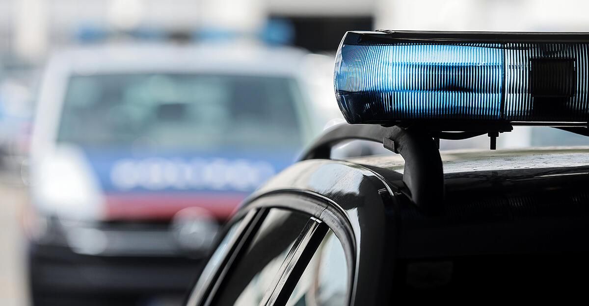 Close up of a police car's blue lights flashing in the foreground, with a blurred police car in the background.