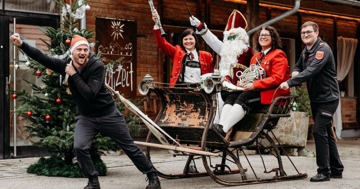 Eine festliche Szene mit dem Weihnachtsmann und seinen Helfern, die in einem Schlitten fahren, wobei eine Person ein Musikinstrument hält.