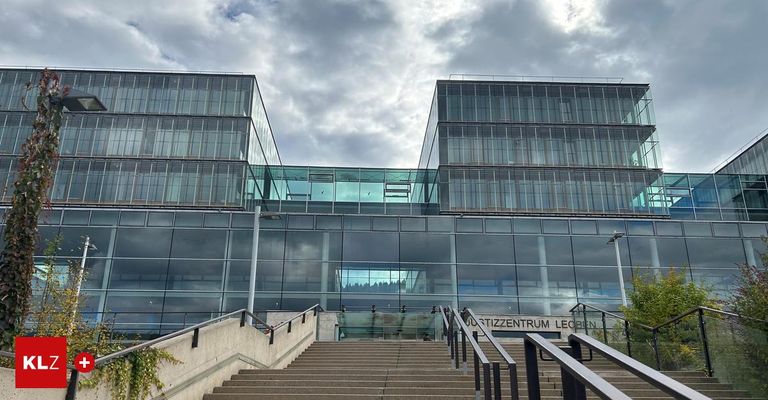 Ein modernes Gebäude mit Glaswänden und einer Treppe, die hinaufführt, umgeben von einem bewölkten Himmel.