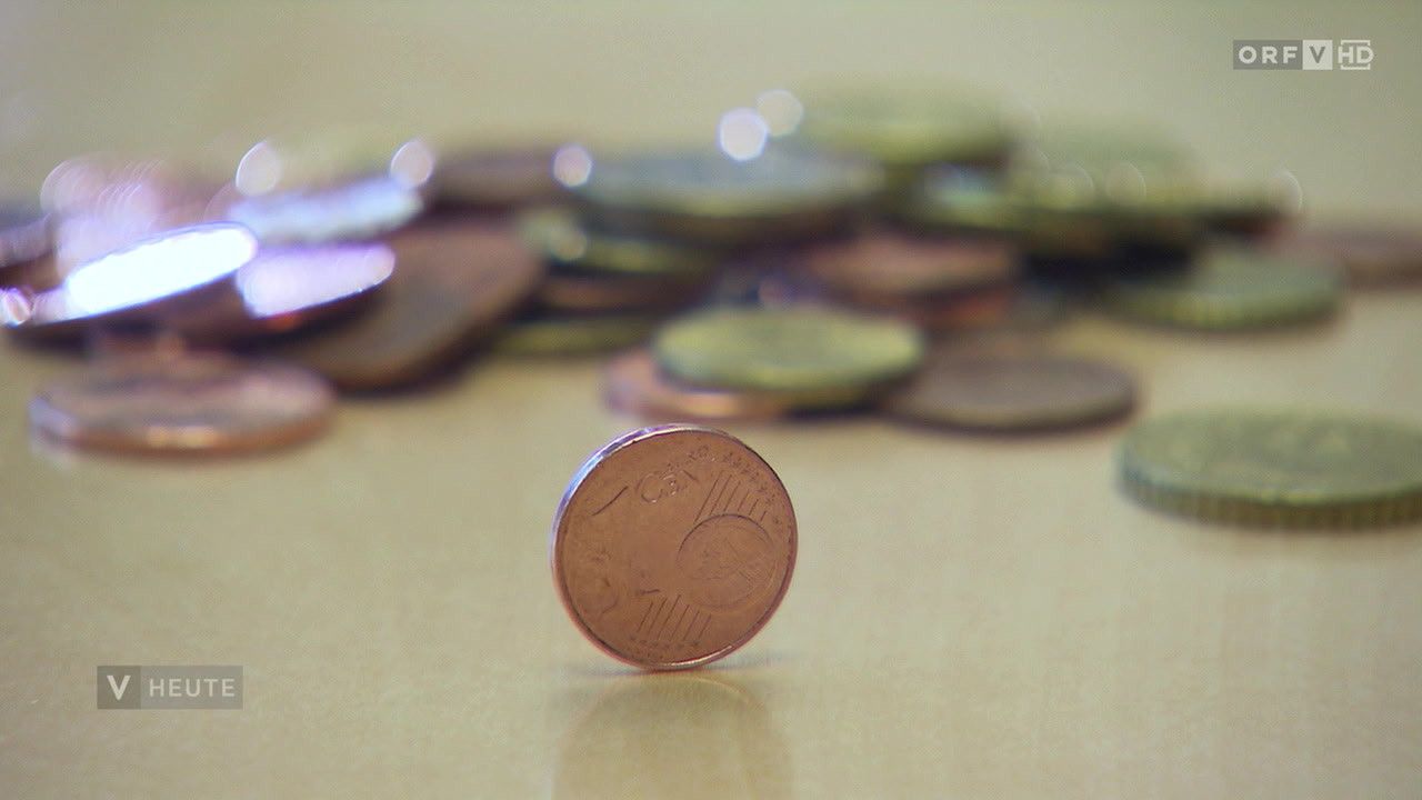 Eine Nahaufnahme einer Euro-Münze, mit einer Ein-Cent-Münze im Vordergrund und anderen Münzen im Hintergrund.