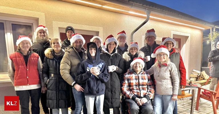 Eine Gruppe von Menschen mit Weihnachtsmützen steht bei Nacht vor einem Gebäude und posiert für ein Foto.