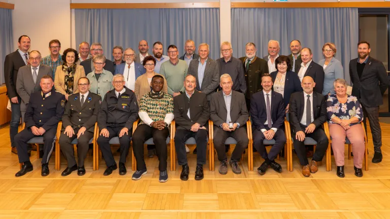 Eine Gruppe von Menschen in Anzügen und Krawatten posiert für ein Foto im Konferenzraum.