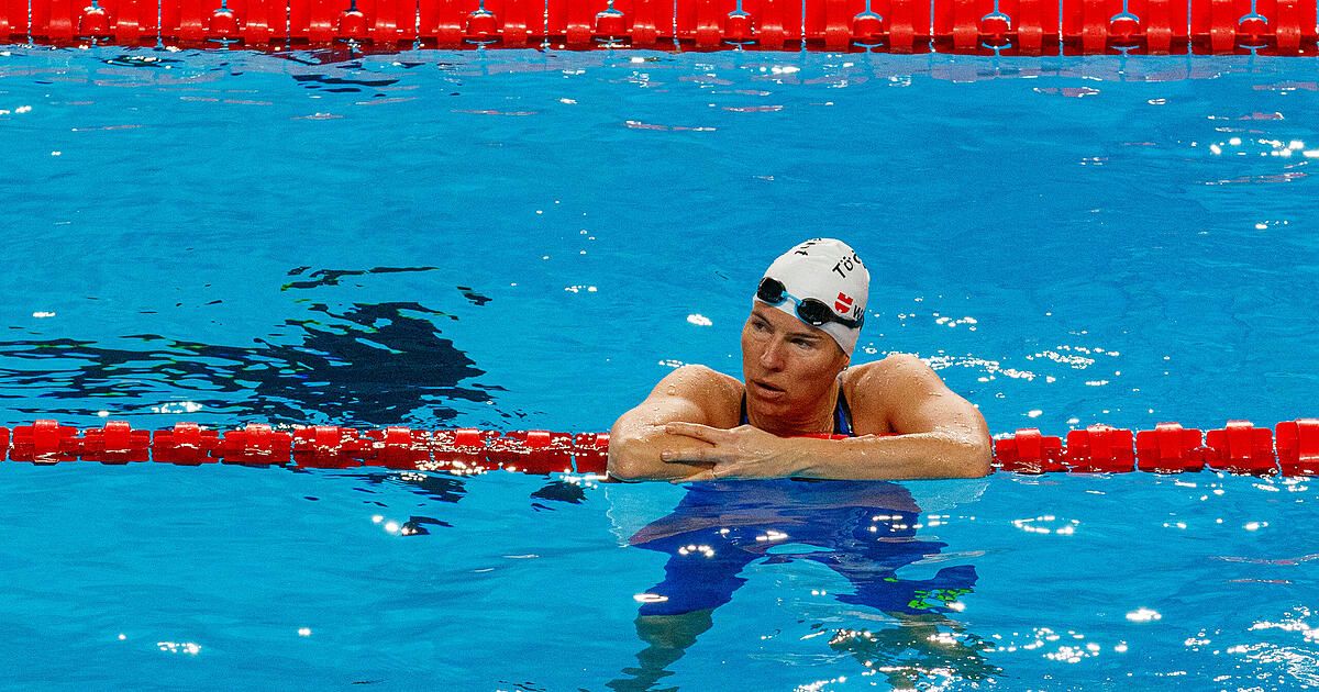 Eine Schwimmerin mit Schwimmmütze, Schwimmbrille und rotem Bahnseil im Pool.