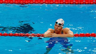 Eine Schwimmerin mit Schwimmmütze, Schwimmbrille und rotem Bahnseil im Pool.